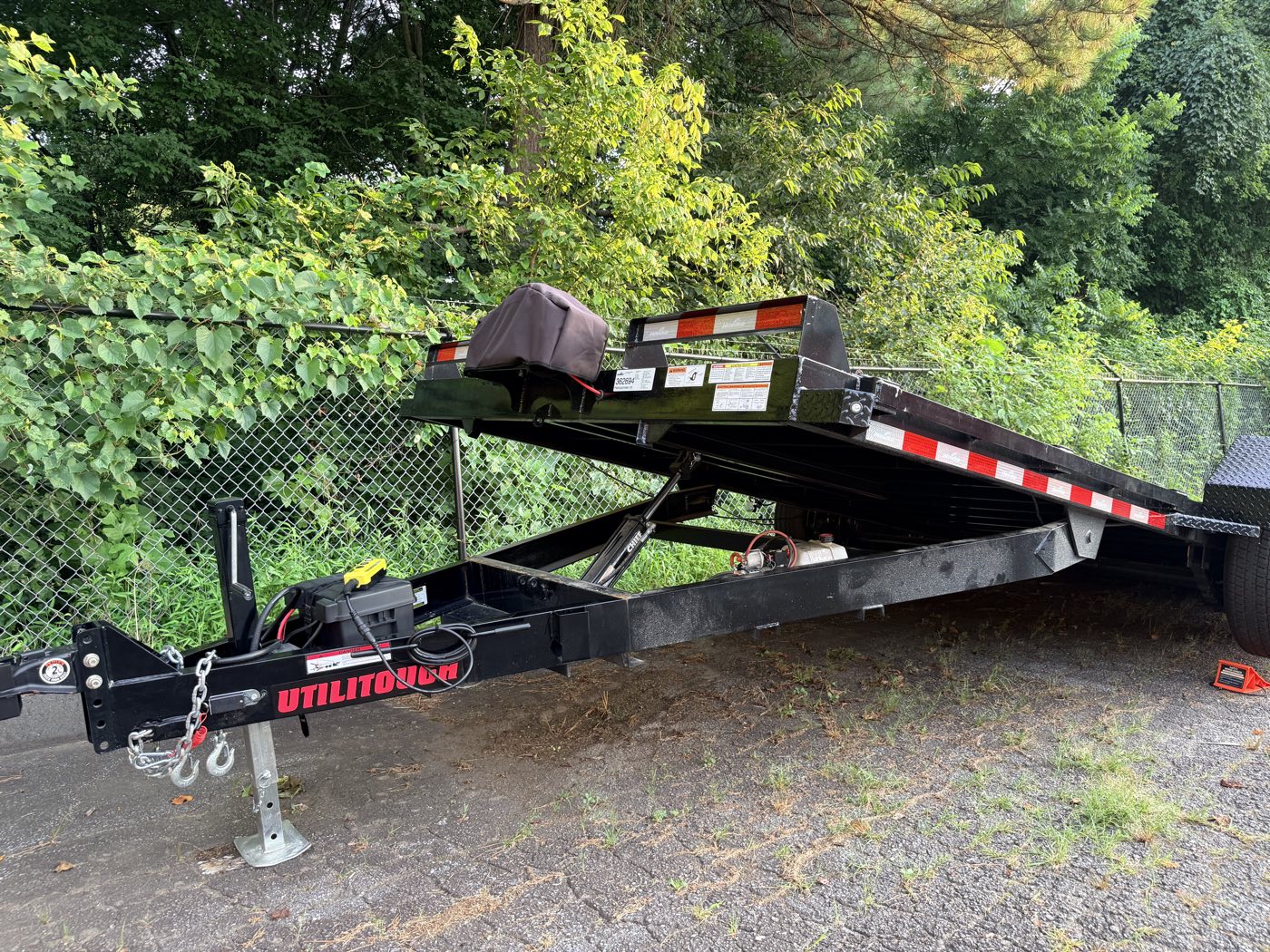 Side view of the trailer with the deck fully tilted up, showing the hydraulic ram